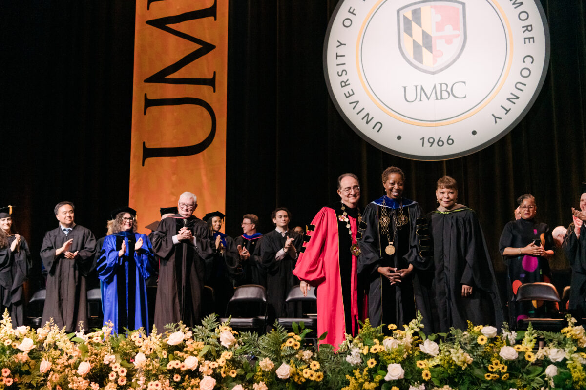 Sheares Ashby stands with University System of Maryland Chancellor Jay Perman and Board of Regents Chair Linda Gooden in front of the UMBC seal at her investiture ceremony.