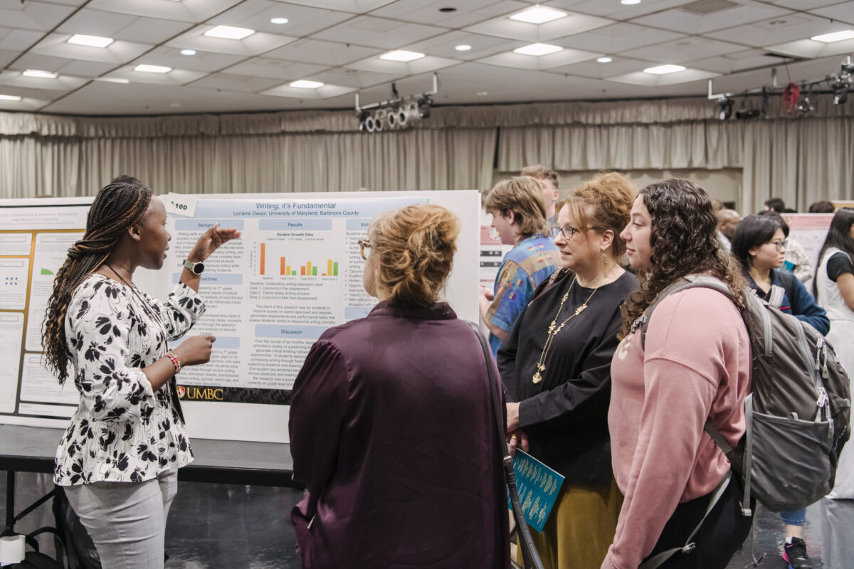 People standing near a poster board presenting research at UMBC's 2024 Undergraduate Research and Creative Achievement Day in 2024.