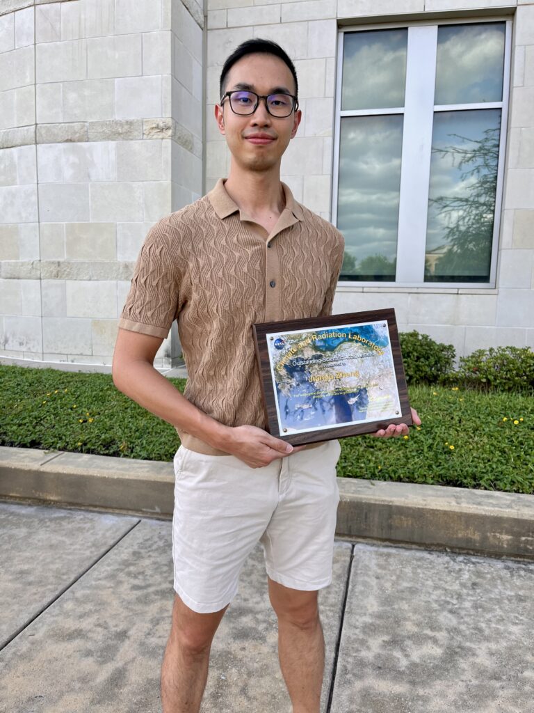 man standing holding plaque on sidewalk outside building