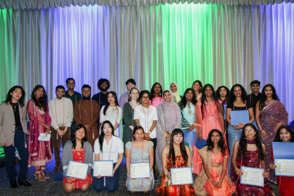 Over twenty Asian, Asian American, and Pacific Islander college students stand together for a celebratory group picture with their award certificates and honor cords